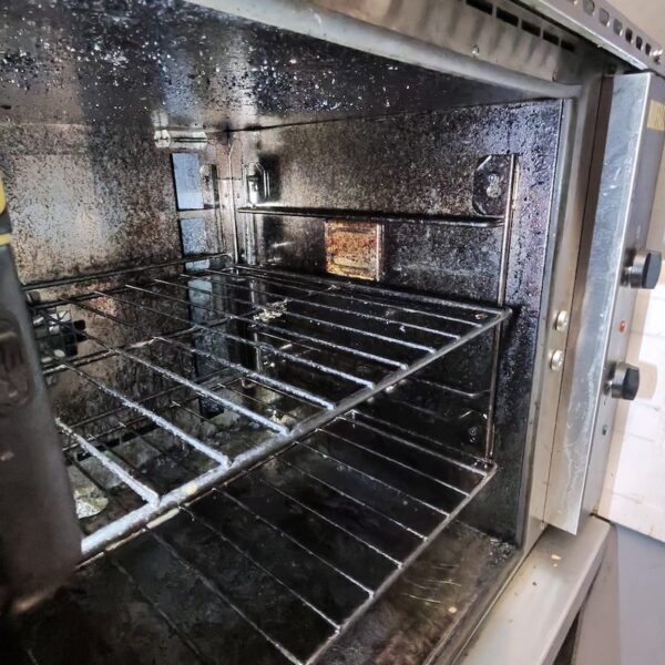 Close-up of grease and carbon build-up inside a Buffalo commercial oven before deep cleaning.