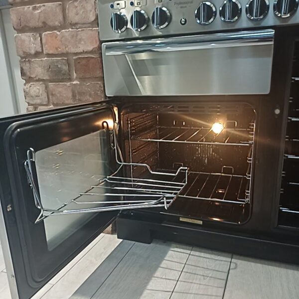 Clean main oven of a Rangemaster Professional in Hopwas, with its glass door open and chrome shelves refitted.