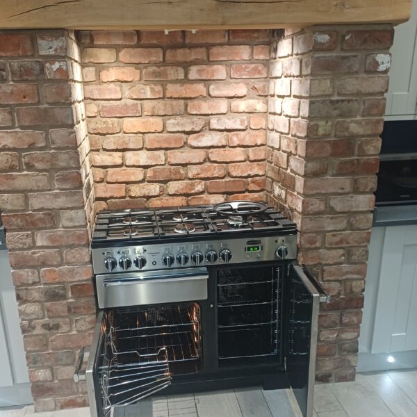 Stainless steel Rangemaster Professional beneath a brick fireplace in Hopwas, with both cleaned oven doors open.