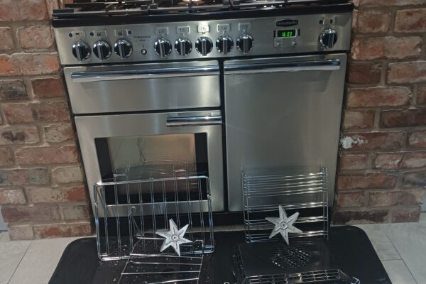Clean stainless steel Rangemaster Professional range cooker in Hopwas with removed shelves, panels and fan covers laid out in front.